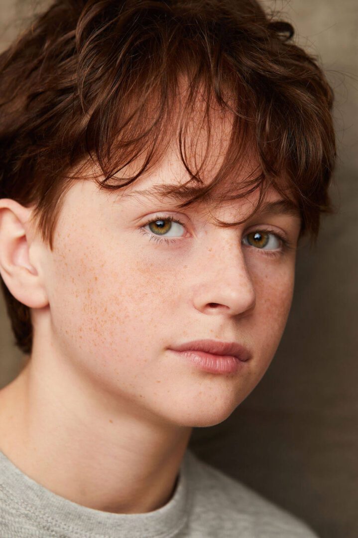 Close-up portrait of a young person with freckles and brown hair.