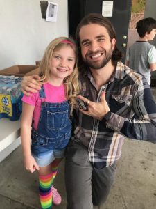 Man and girl smiling, posing together indoors.