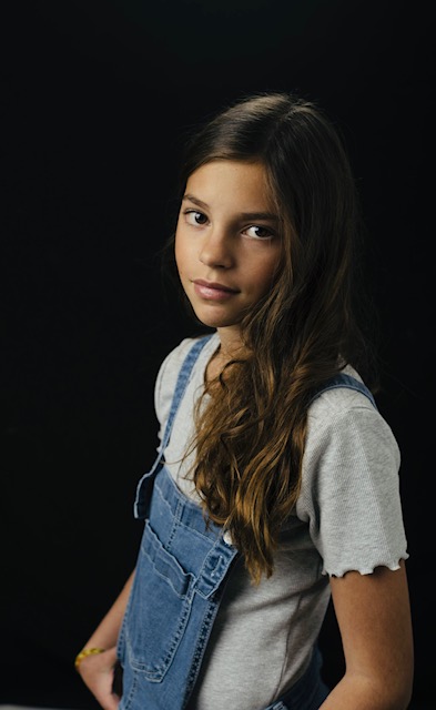 Portrait of a young girl with long hair against a dark background.